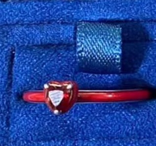Anillo con corazón rojo sobre banda rosa